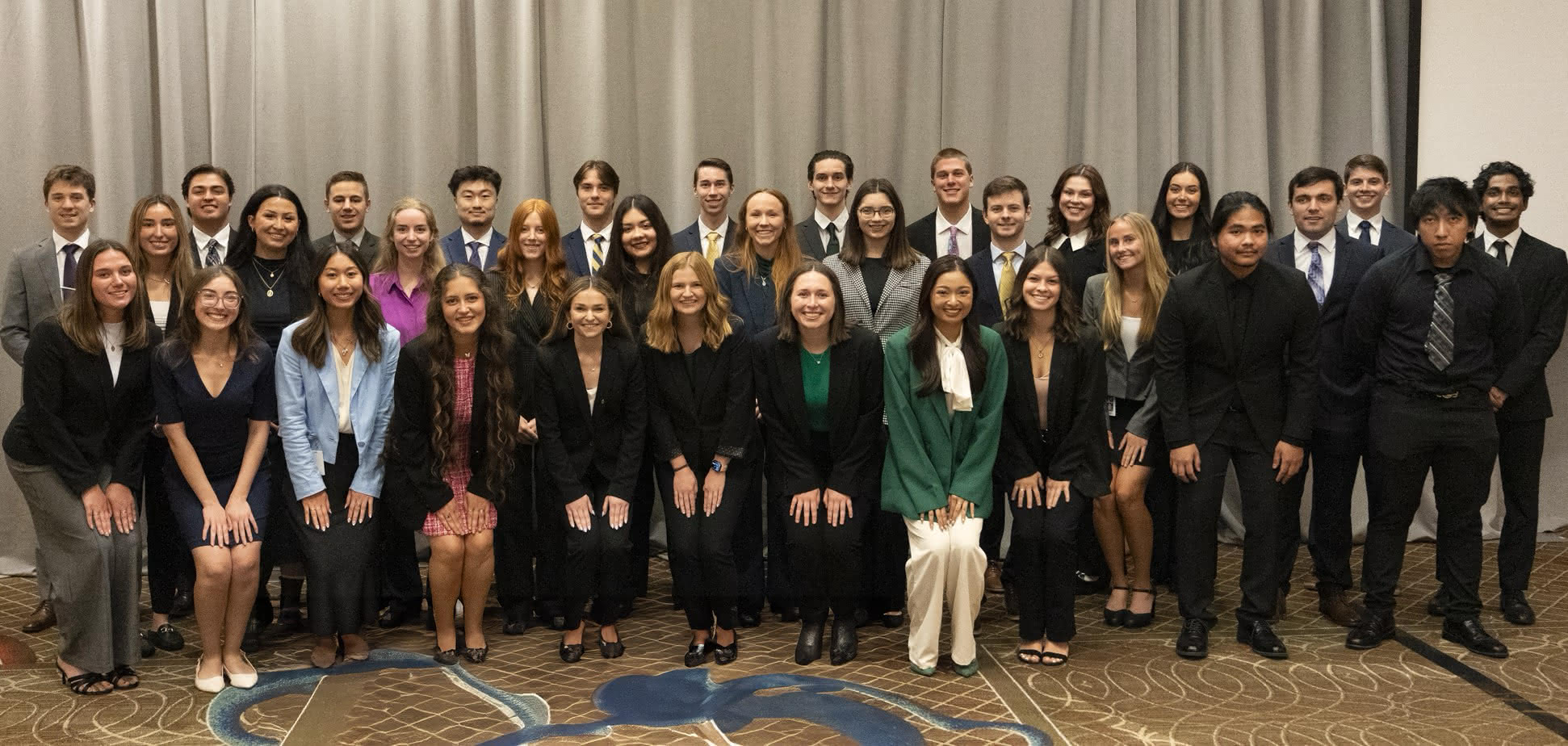 The full intern cohort standing together dressed in business attire