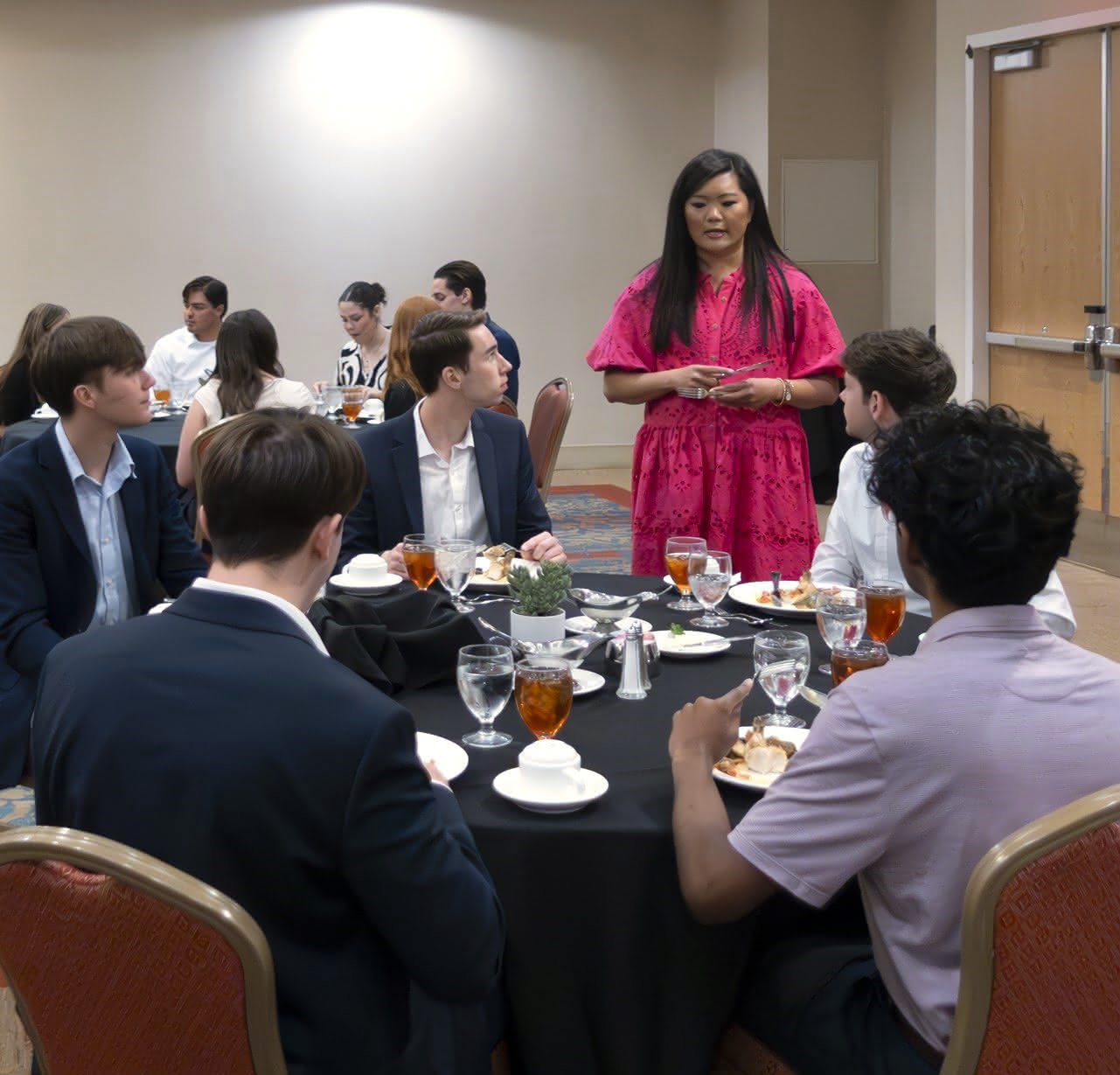 Interns in dress atire sitting at a circular table eating dinner